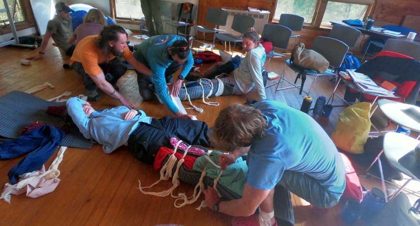 A group of people appear to be practicing leg bracing as a part of a WFR course. 